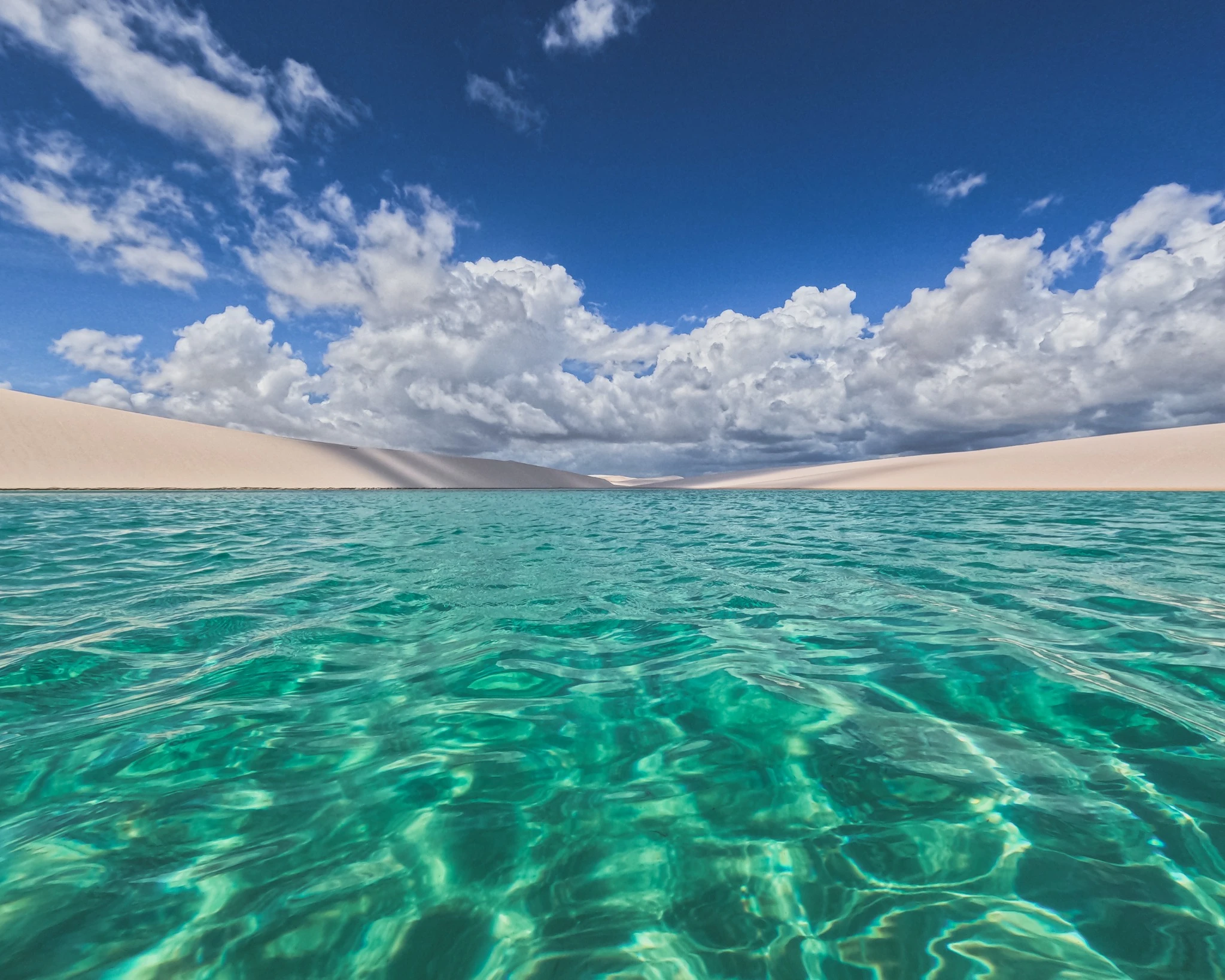 Praia do Preá vista do alto: faixa larga de areia clara, mar verde e coqueiros, quase sem construções
